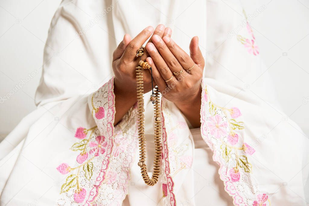Muslim woman praying close up image of hands as she holds prayer beads,tasbih - religious, Islam, concept image with copy space for text