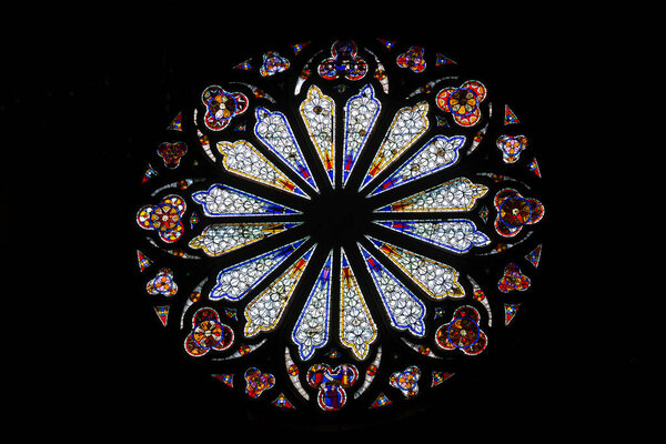 Beautiful stained glass on a black background in the Cathedral of Peter and Paul in Wissembourg. Images of saints. The sun breaks through the stained-glass windows.