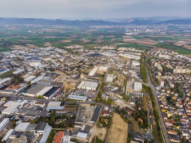 Küçük Alman şehri Viernheim 'ın en iyi manzarası. Arka planda yeşil alanlar ve dağlar var. Farklı evler ve yollar. Depolar ve işletmeler.