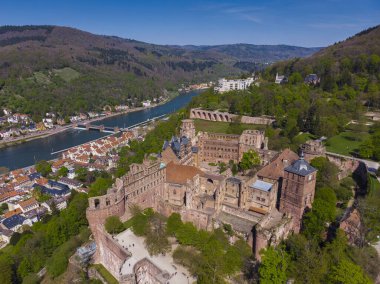 Heidelberg kalesinin ve şehrin eski kısmının güzel manzarası. Bahar. Ağaçlarda yeşil yapraklar. Nekka Nehri. Nehrin üzerindeki yaya köprüsü. Güzel dağlar.