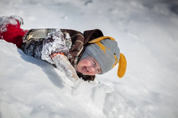 Kırmızı pantolonlu küçük yakışıklı bir çocuk ve kahverengi bir kuzu derisi ceket kar yığınları arasında yol alıyor. Çocukla oynanıyor..