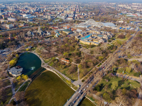 Top view on Secheni baths, Budapest city park. People are resting on the green grass. Lakes and bridge in the park. Spring. Trees without leaves and with green leaves.