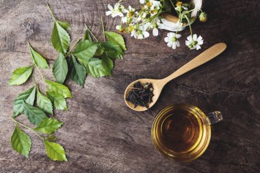 Fincan çay ve yaprakları ve eski woode üzerinde tahta kaşık kuru çay