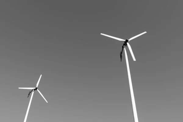 Zwei Windkraftanlagen mit blauem Himmelshintergrund auf schwarz-weißem Ton. — Stockfoto