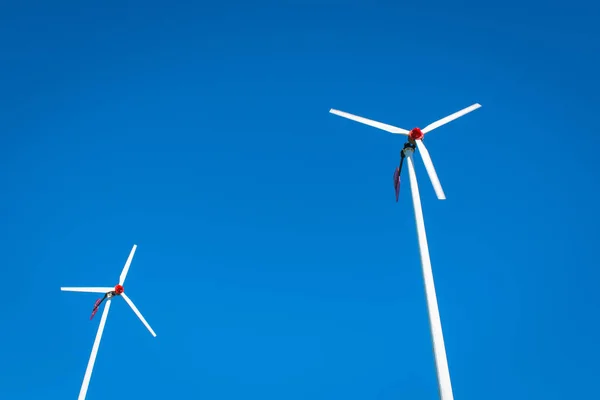Two Wind turbines with blue sky background with copy space