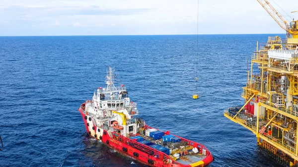 Plataforma de procesamiento de petróleo y gas, grúa elevando carga a carga para suministrar barco sobre el mar — Foto de Stock