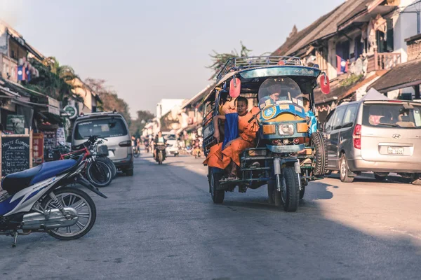 Conductor en tuk-tuk estacionado encendido mientras que lleva monje joven en el mor — Foto de Stock
