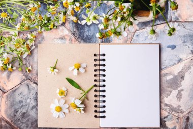 Boş defter ile beyaz çiçek ve bas ket çiçek kopya alanı ile vintage mermer tabloda yukarıdan görünüm