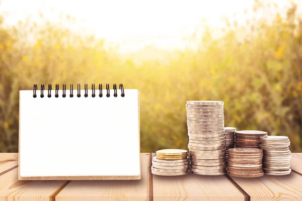 Stack of coins with blank notepad on wooden board, business and — Stock Photo, Image