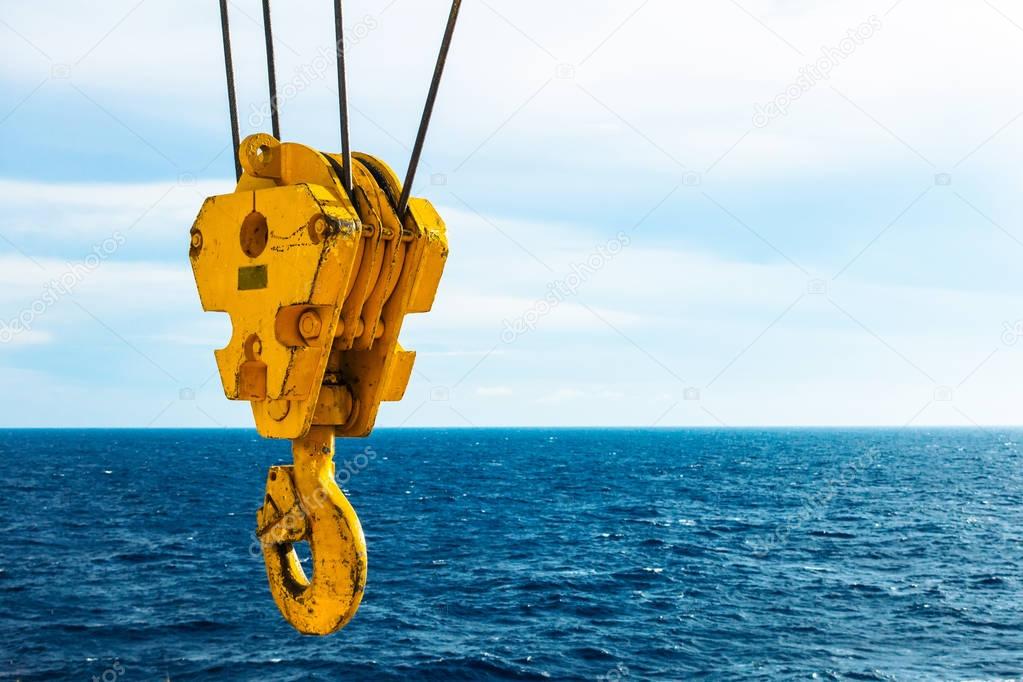 Crane hook in the sea with sky and clouds background on offshore