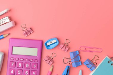 Sabit kavramı, üstten görünüm fotoğraf makas düz yatıyordu, kurşun kalem, ataç, hesap makinesi, yapışkan not, zımba ve pembe arka plan kopya alanı ile pembe ve mavi tonu Not Defteri'nde.
