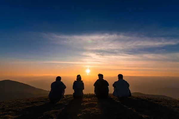 Silhueta de amigos sentados juntos assistindo por do sol para busi — Fotografia de Stock