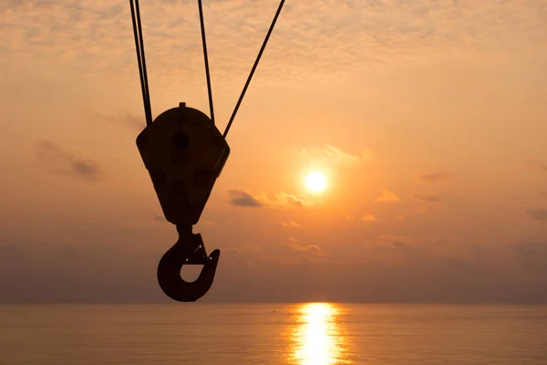 Kraan haak silhouet op zonsondergang tijd met zee achtergrond in offs — Stockfoto