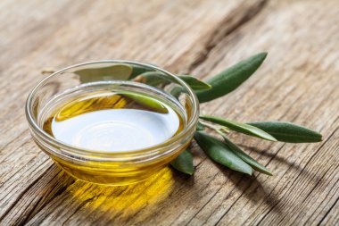 Zeytinyağı ve zeytin dal ahşap bir masa üzerinde