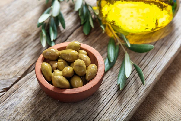 Botella de aceite de oliva y aceitunas sobre una mesa — Foto de Stock