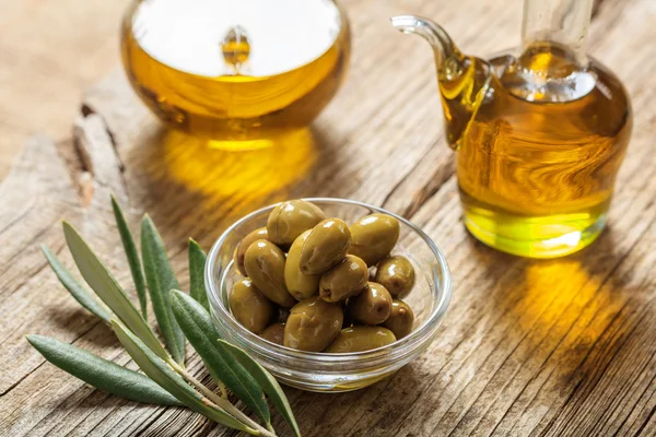 Оливки и оливковое масло на столе — стоковое фото