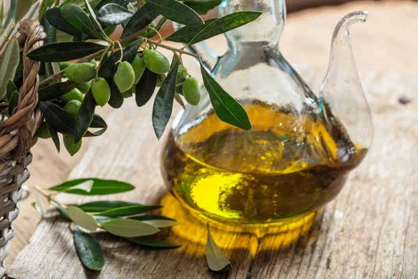 Olio d'oliva e ramoscello d'oliva su un tavolo — Foto Stock