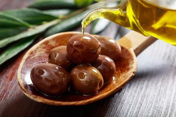 Träsked med oliver och olivolja — Stockfoto