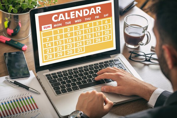 Man working on a laptop - calendar on the screen