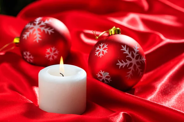 Χριστούγεννα μπάλες και κερί σε κόκκινο φόντο σατέν — Φωτογραφία Αρχείου