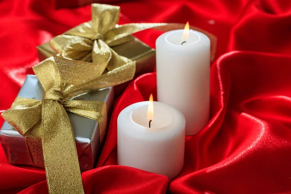 Κουτιά δώρων και κεριά στο κόκκινο σατέν — Φωτογραφία Αρχείου