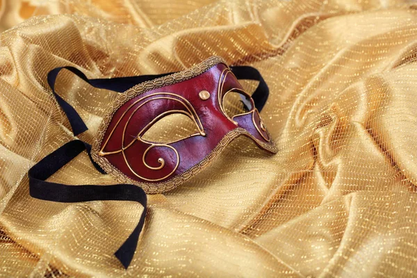 Карнавальная маска на золотом атласном фоне — стоковое фото