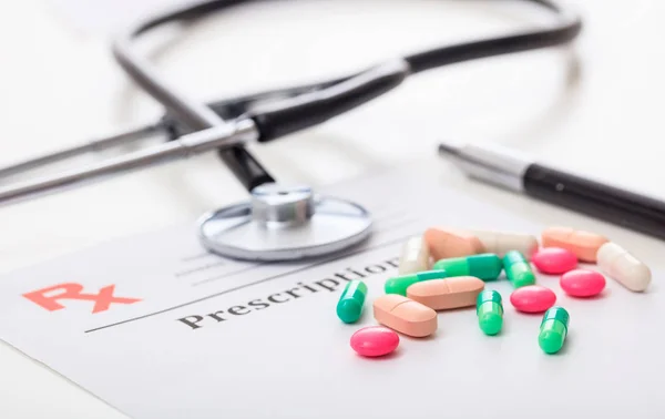 Pillen en een stethoscoop op een lege recept — Stockfoto