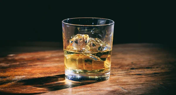 Whisky de vidrio y cubitos de hielo en mostrador de madera — Foto de Stock