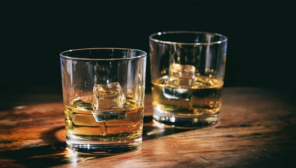 Glazen whisky en ijsblokjes op houten teller — Stockfoto