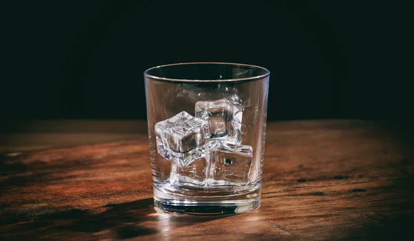 Glas mit Eiswürfeln auf Holztheke — Stockfoto
