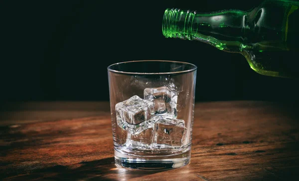 Glas met ijsblokjes op houten teller — Stockfoto