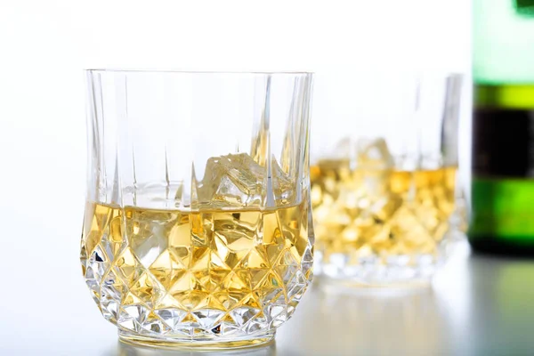 Glasses of whiskey and ice on white background — Stock Photo, Image