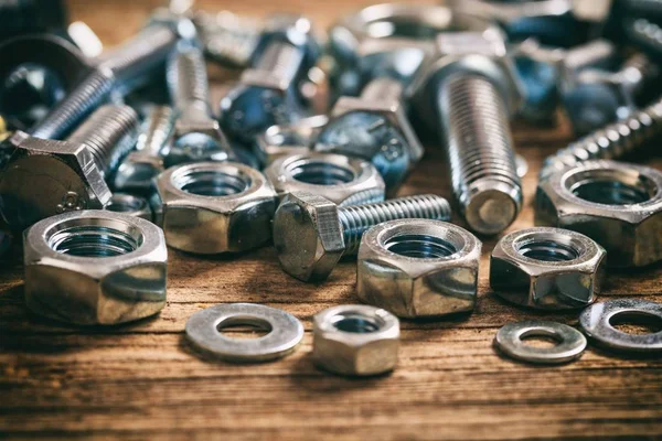 Pernos y tuercas sobre fondo de madera — Foto de Stock