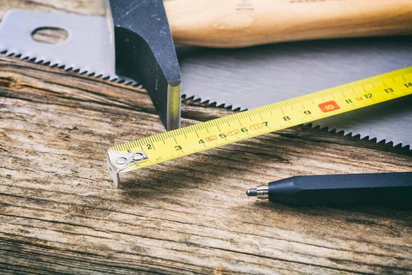 Hamer en hand zag op houten achtergrond — Stockfoto