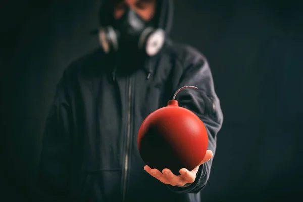 Человек в капюшоне с красной бомбой — стоковое фото