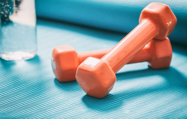 Hanteln und eine Flasche Wasser auf einer Yogamatte — Stockfoto