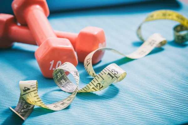 Kurzhanteln und Maßband auf einer Yogamatte — Stockfoto