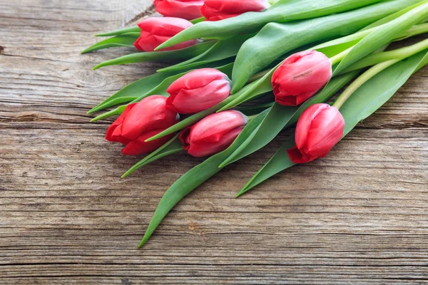 Červené tulipány na dřevěné pozadí — Stock fotografie
