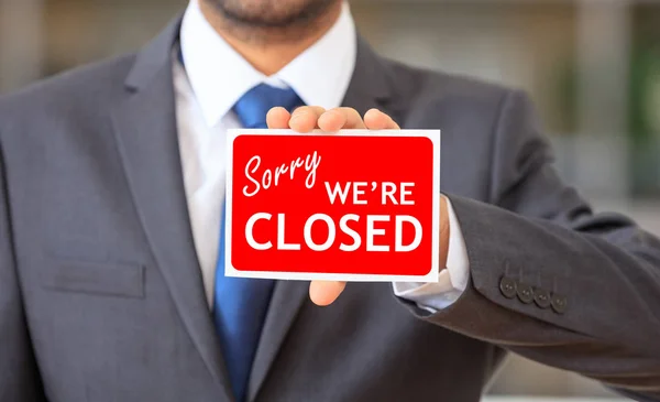 Man holding a sorry we are closed sign — Stock Photo, Image