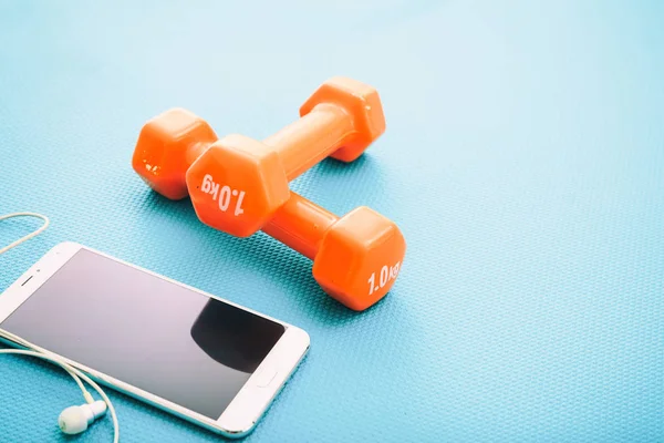 Dumbbells and smartphone on a yoga mat — Stock Photo, Image