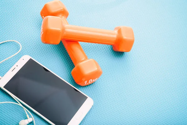 Dumbbells and smartphone on a yoga mat — Stock Photo, Image