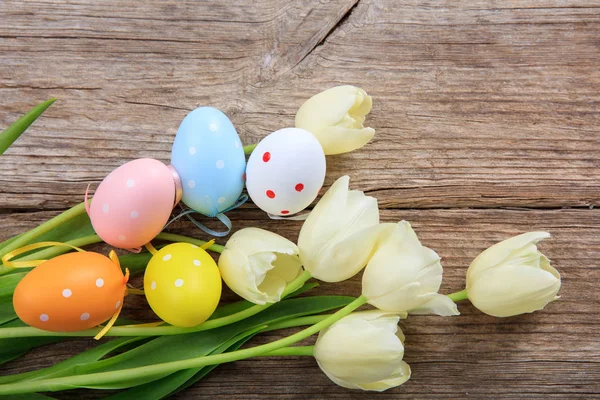 Paaseieren en tulpen op houten achtergrond en kopie ruimte — Stockfoto