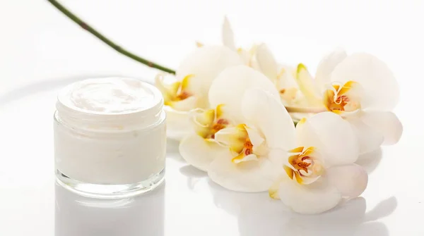 Crème hydratante et orchidée sur fond blanc — Photo