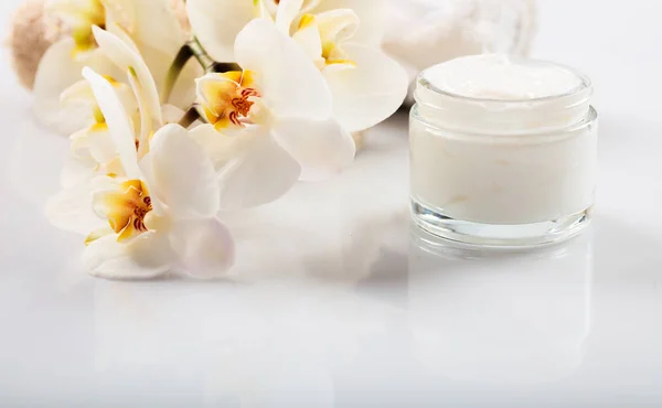 Creme hidratante e orquídea sobre fundo branco — Fotografia de Stock