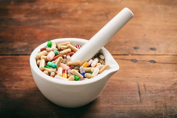 Pastillas en un mortero sobre fondo de madera — Foto de Stock