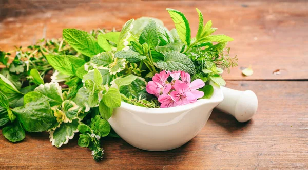 Herbs in a mortar on wooden background — Stock Photo, Image