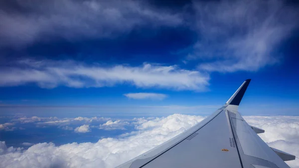 Plane wing over clouds on a blue sky background — Stock Photo, Image