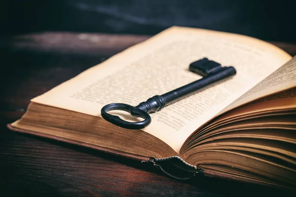 Ключ на старовинній книзі на дерев'яному фоні — стокове фото