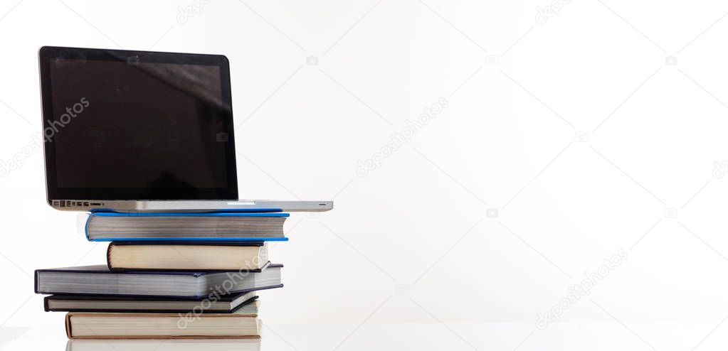 Books stack and a laptop on white background