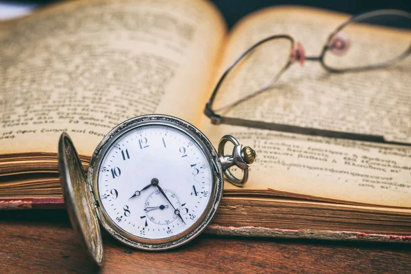 Pocket watch och öga glasen på en gammal bok — Stockfoto